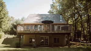 A two-story house with a balcony, wooden railings, and a chimney. - Cedar Point Cottage- Perfect Lake Michigan Retreat (Mears)