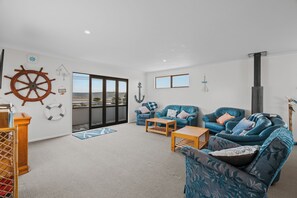 A spacious living area with a large window, two sofas, a wooden coffee table, and a wooden side table.