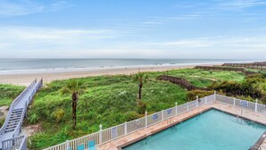 Une piscine avec une terrasse en bois et vue sur la plage.