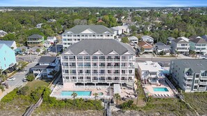 Un grand hôtel avec de nombreux étages, une piscine et un parking.