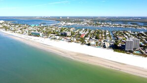 An aerial view of a coastal town with a beach, marina, and residential buildings. -   160 inch pool tv plus 120 inch great room tv  6 Bed  5 Bath Pool and hot tub (Fort Myers Beach)