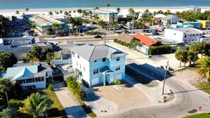 A coastal town with a prominent blue building, a beach, and palm trees. -   160 inch pool tv plus 120 inch great room tv  6 Bed  5 Bath Pool and hot tub (Fort Myers Beach)