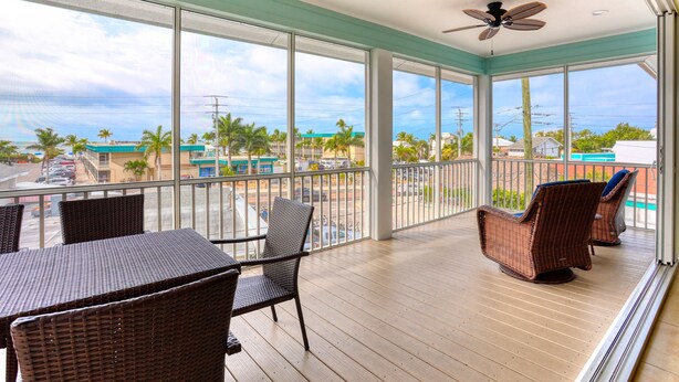 A balcony with wicker furniture, large windows, and a ceiling fan. -   160 inch pool tv plus 120 inch great room tv  6 Bed  5 Bath Pool and hot tub (Fort Myers Beach)
