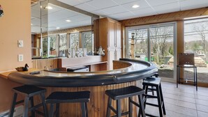 A kitchen with a curved bar area, wooden cabinets, and large windows. - Repeat Retreat — Your Place to Come Back To! (Lake Harmony)