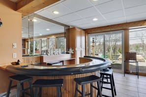 A kitchen with a curved bar area, wooden cabinets, and large windows.