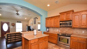 A kitchen with wooden cabinets, a microwave, an oven, and a ceiling fan.