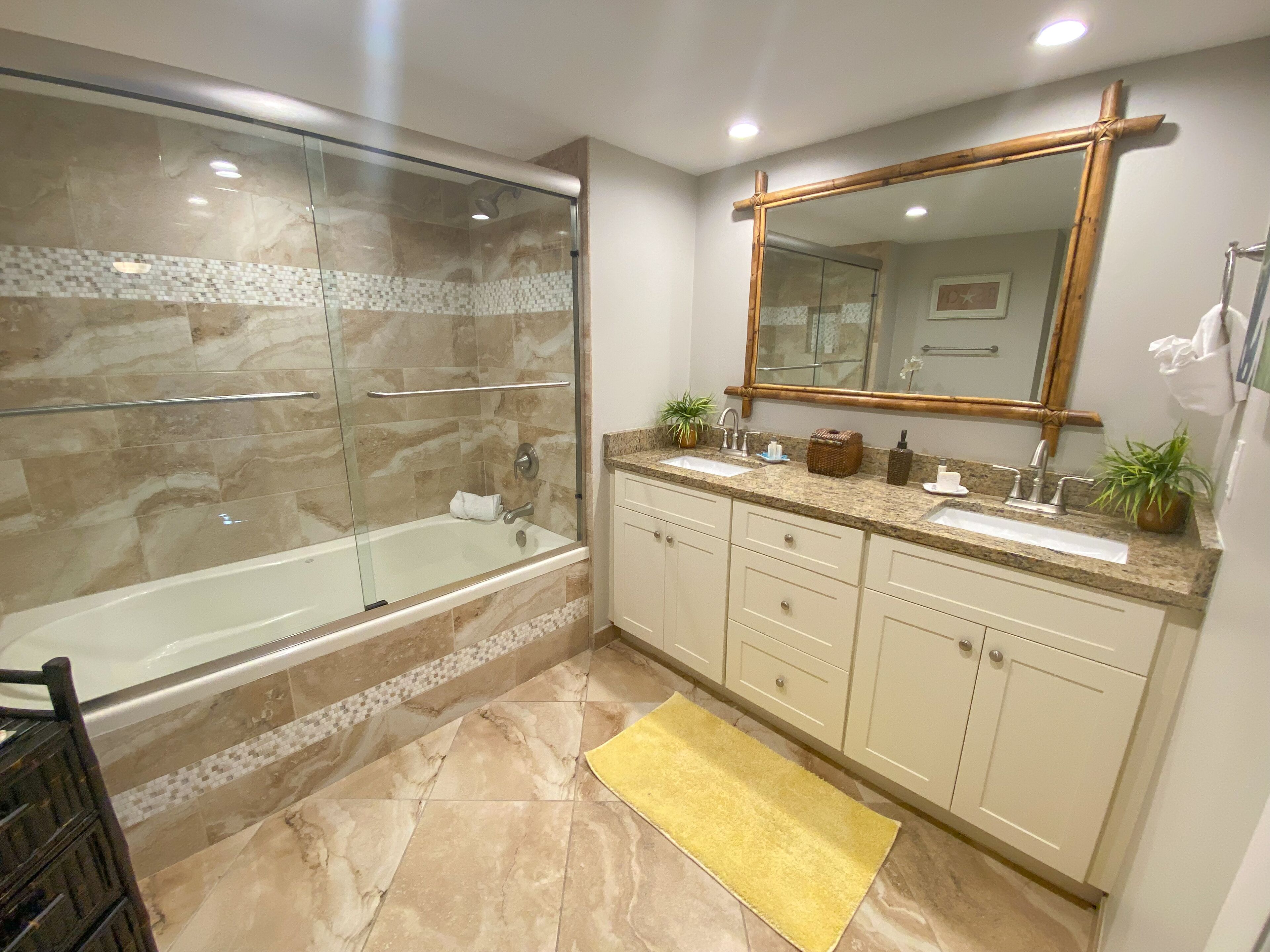 Une salle de bain moderne dotée d’une douche à parois de verre, d’un grand miroir et d’un meuble-lavabo avec un évier et un plan de travail.