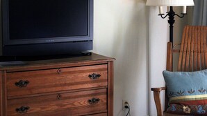 A television on a wooden dresser, a lamp, and a chair with a cushion. - Private En Suite Large Master Bedroom With King Sized Bed   (Burlington)