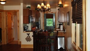Una cucina con mobili in legno, un lampadario e una finestra con persiane.