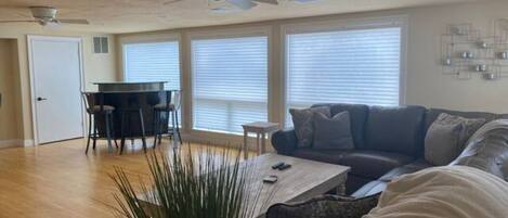 A spacious living room with a large couch, a coffee table, and a dining area with a table and chairs.