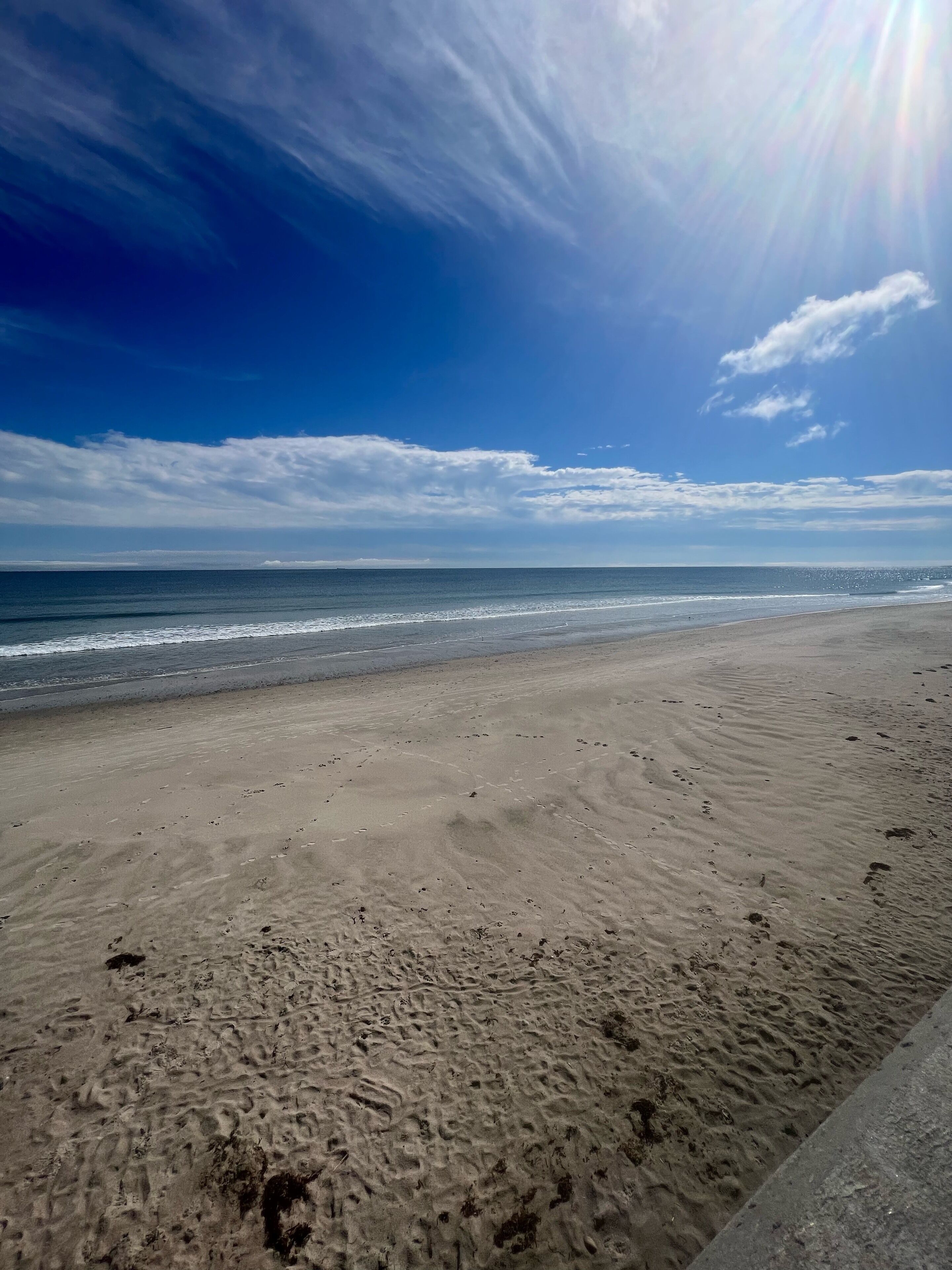 Una playa con una amplia orilla arenosa y un cielo azul despejado.