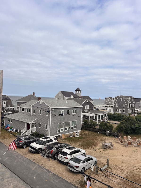 A residential area with houses, a parking lot, and a sandy ground.