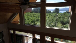 A room with multiple windows offering views of a lush landscape and a lake.