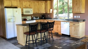 A kitchen with wooden cabinets, a refrigerator, a microwave, a coffee maker, and a sink.