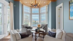 A room with a large bay window, a chandelier, and a seating area with two sofas and a coffee table. - Unwind in Ultimate Luxury: Ridgeview Manor, Boone's Mountain Masterpiece (Boone)