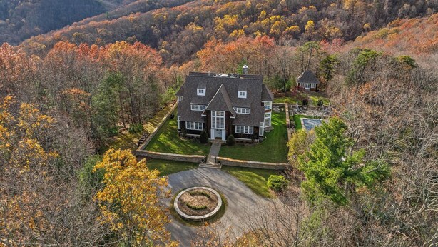 A large house with a well-maintained lawn and a circular driveway, surrounded by autumn-colored trees and hills in the background. - Unwind in Ultimate Luxury: Ridgeview Manor, Boone's Mountain Masterpiece (Boone)