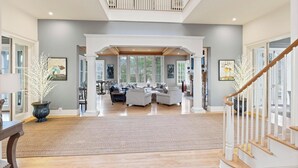A spacious living area with a high ceiling, a staircase, and a view of the outdoors. - Unwind in Ultimate Luxury: Ridgeview Manor, Boone's Mountain Masterpiece (Boone)