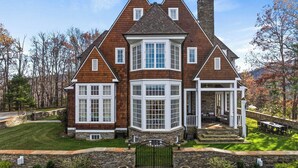 A large, two-story house with a stone foundation, multiple windows, and a stone chimney. - Unwind in Ultimate Luxury: Ridgeview Manor, Boone's Mountain Masterpiece (Boone)