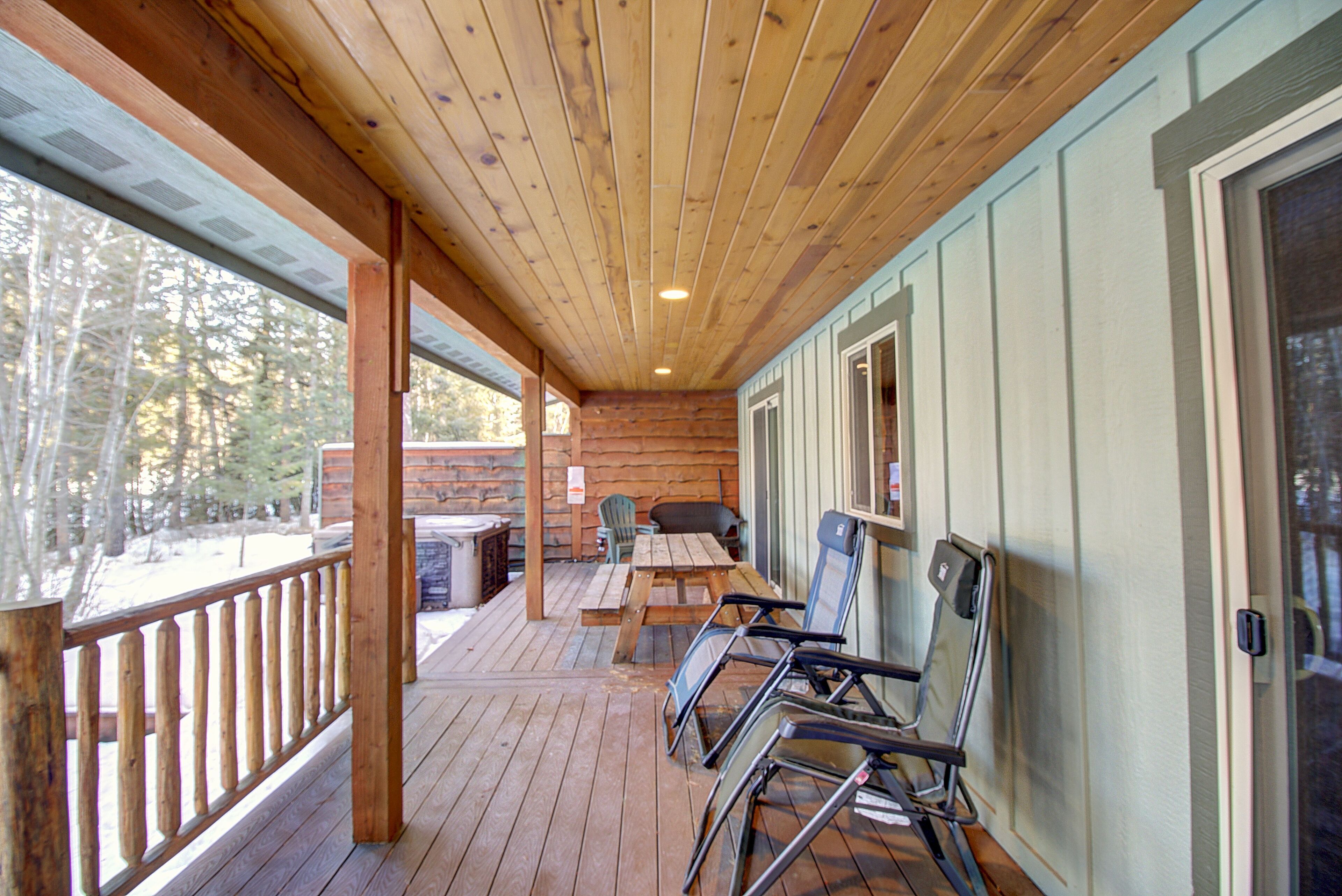 A wooden deck with a wooden railing, a table, and chairs.