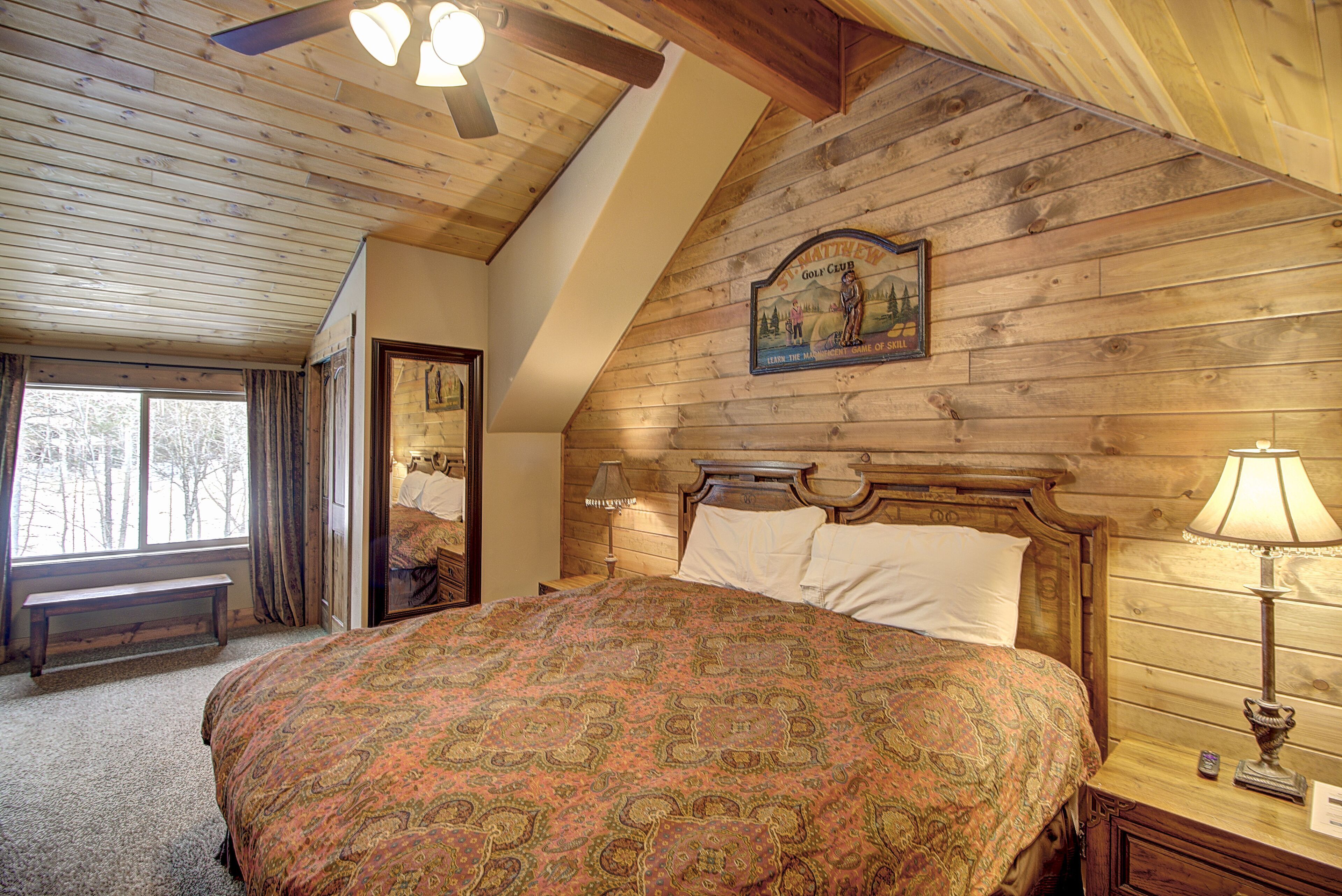 Een slaapkamer met een groot bed, houten plafond en een bordje aan de muur.