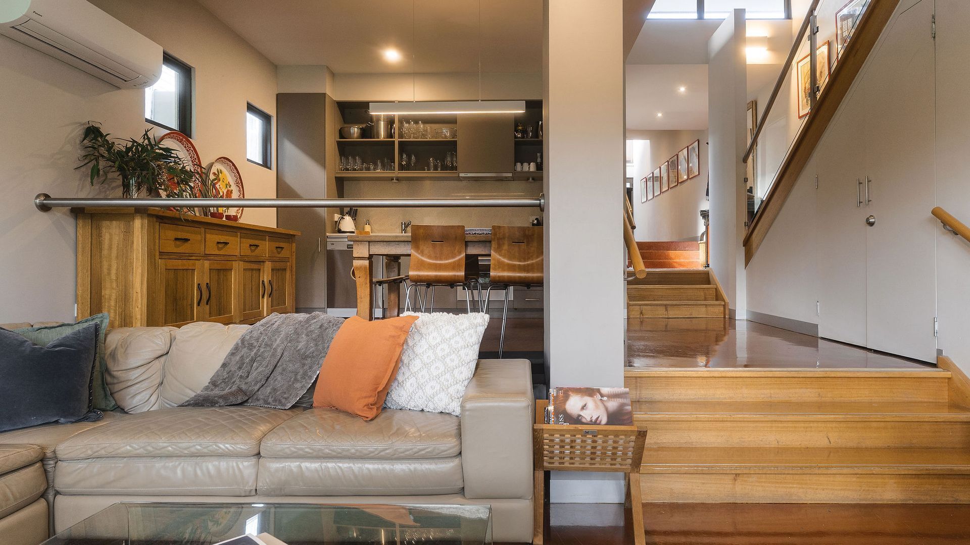 A modern living room with a leather sofa, a coffee table, and a staircase leading to an upper level.