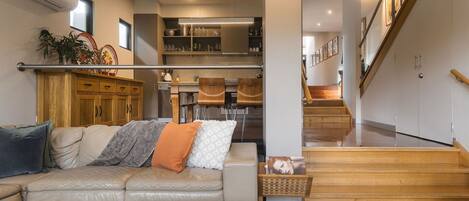 A modern living room with a leather sofa, a coffee table, and a staircase leading to an upper level.