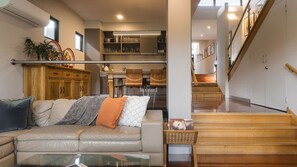 A modern living room with a leather sofa, a coffee table, and a staircase leading to an upper level. - Lake Daylesford Lodge 7 ~ 3 Bedroom/3 Ensuite (Daylesford)