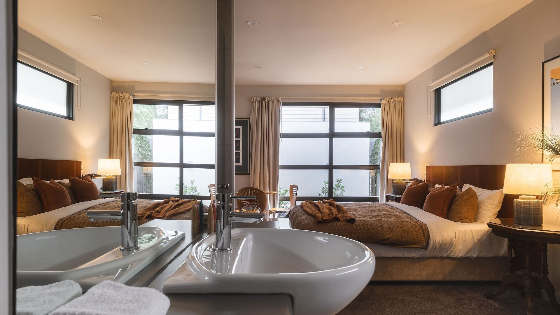 A hotel room with a large bed, a separate bathroom with a bathtub, and large windows providing natural light.
