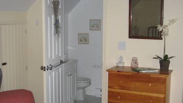 Een badkamer met toilet, een houten dressoir en een spiegel.