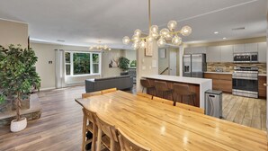 Eine moderne Küche mit Edelstahlgeräten, einem Holzespeisetisch und einem großen Fenster.