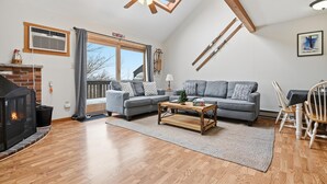 Een woonkamer met een open haard, twee banken, een salontafel, en een eethoek met stoelen.