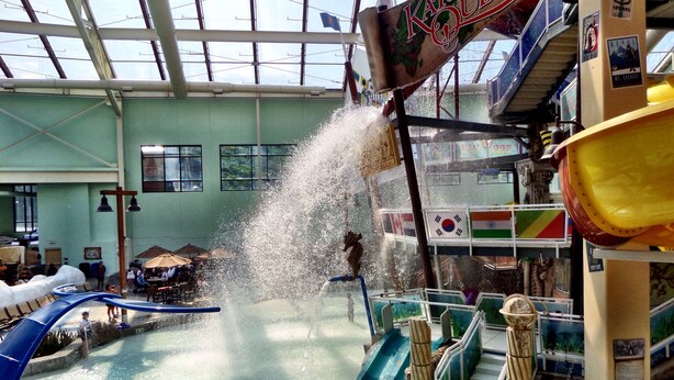 Een overdekt waterpark met glijbanen en een grote waterfontein.