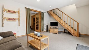 Een woonkamer met een houten trap, een bank, een salontafel en een televisie.