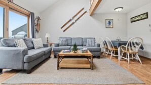 Een woonkamer met een bank, salontafel en een eethoek.