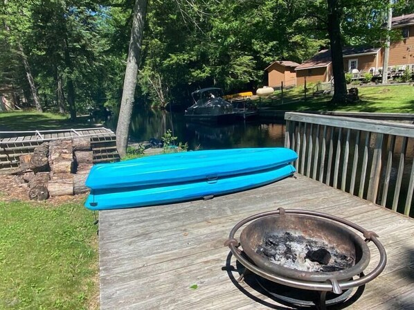 A wooden deck with a blue floating dock and a metal fire pit.