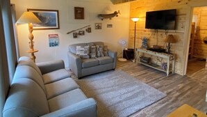 Una sala de estar acogedora con un sofá, una mesita con una lámpara, un televisor y una chimenea.