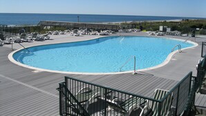 A pool with lounge chairs and a view of the ocean. - CottageVacations4u "Ocean Paradise" -Ocean views! -pool club-dog friendly- elevator (Ocean Isle Beach)