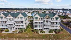 A coastal residential area with multi-story buildings featuring balconies and a central courtyard. - CottageVacations4u "Ocean Paradise" -Ocean views! -pool club-dog friendly- elevator (Ocean Isle Beach)