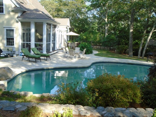 Relax in a serene garden setting, surrounded by a pool and lounge area.