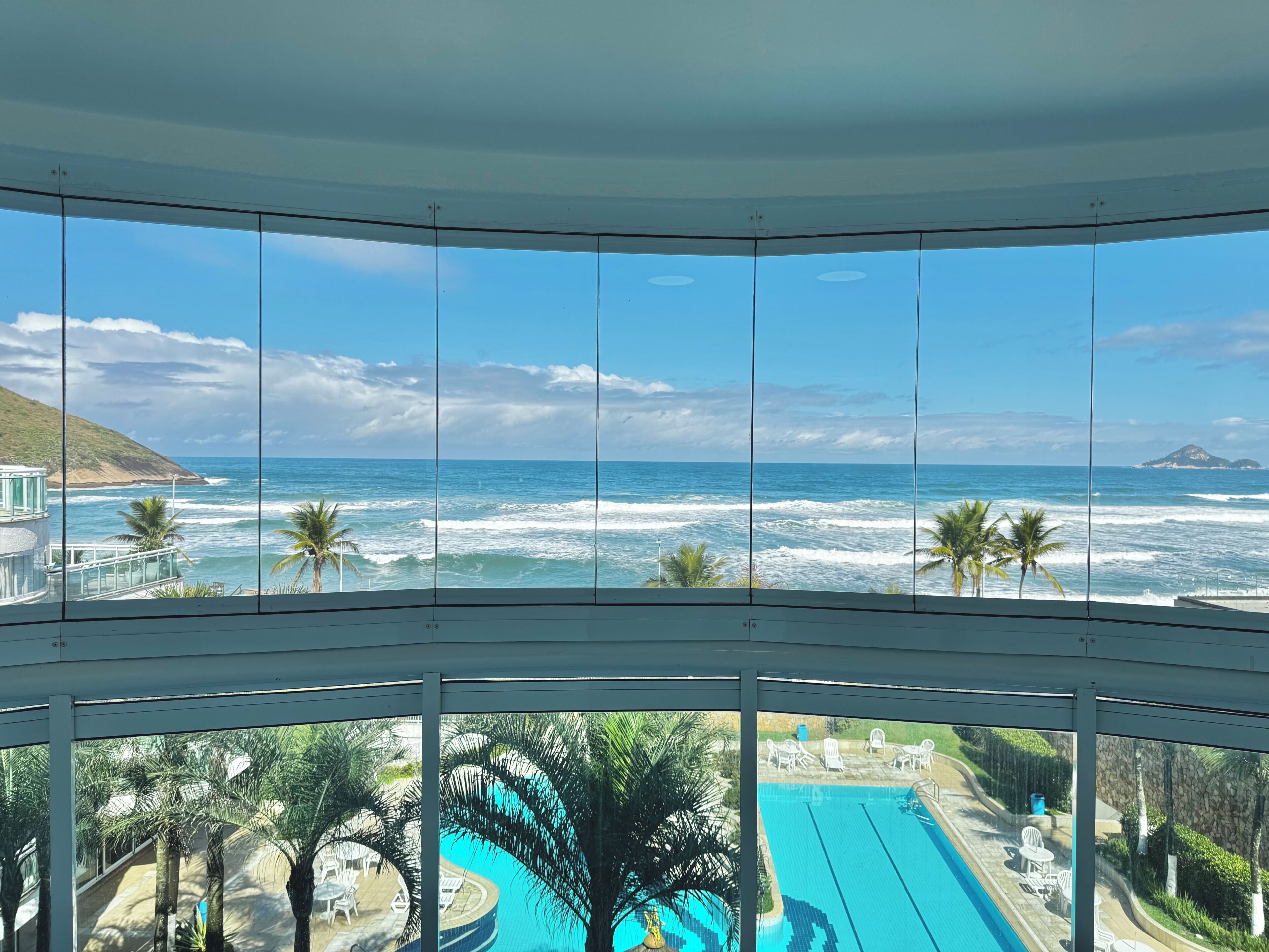 A pool with a view of the ocean and palm trees.