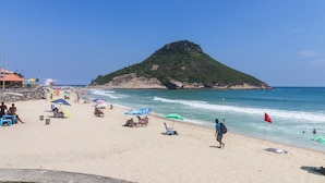 A beach with umbrellas, people, and a flag. - Pontal Beach Ocean View (Rio de Janeiro)