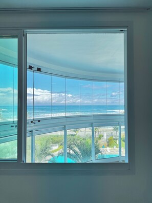 A room with a large window overlooking a beach and ocean.
