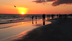 Une scène de plage où l’on voit des personnes se promener le long du rivage au coucher du soleil.