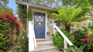 A house with a blue door, white steps, and a garden with various plants and flowers. - Seaside Cottage - Romantic Haven by the Beach (Montecito)