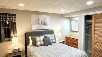 A bedroom with a bed, nightstands, a dresser, a closet, and a painting on the wall.