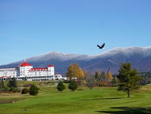 A large building with a red roof, surrounded by a green landscape and mountains in the background. - Affordable Luxury! 4per. Efficiency Ski-out  Condo at Bretton Woods (Caroll)
