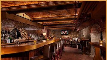 Una zona de bar rústica con vigas de madera, paredes de ladrillo y una barra alargada.