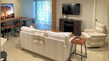 Una sala de estar con sofá, sillones, televisor, chimenea y un comedor con mesa y sillas.