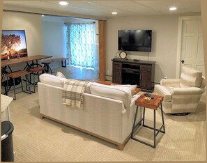 A living room with a sofa, armchairs, a TV, a fireplace, and a dining area with a table and chairs. - Affordable Luxury! 4per. Efficiency Ski-out  Condo at Bretton Woods (Caroll)