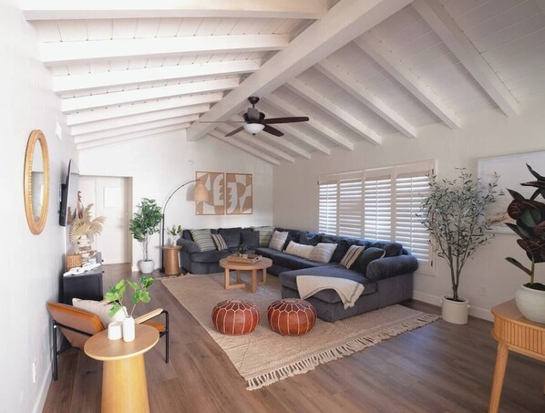 A modern living room with a sectional sofa, a round coffee table, and a ceiling fan.